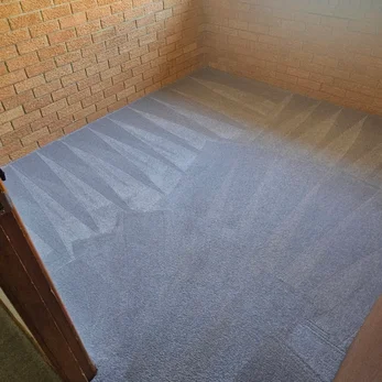 Grey carpet in a brick-walled room, straight after cleaning
